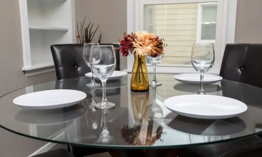 Glass dining table with plates and glasses on it.