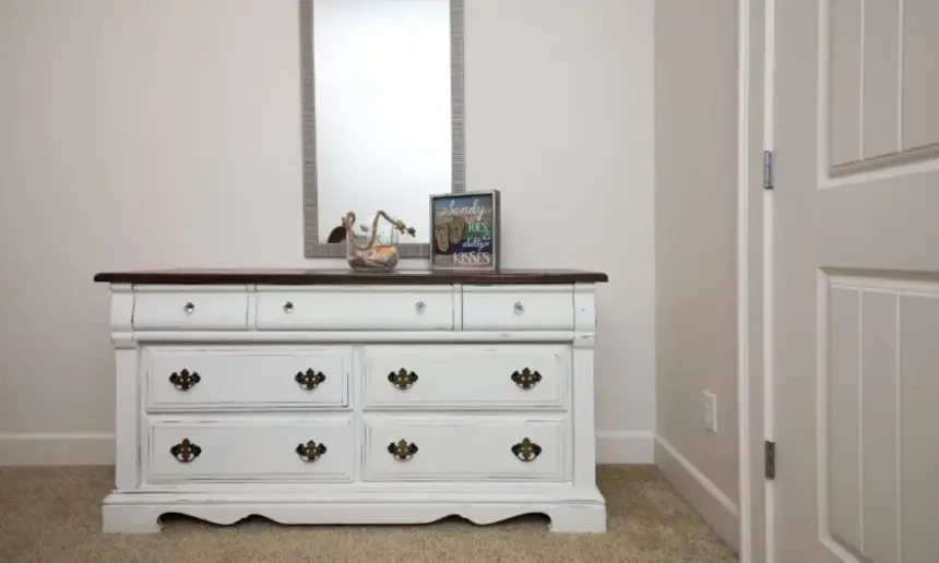 White dresser with vertical mirror over it.