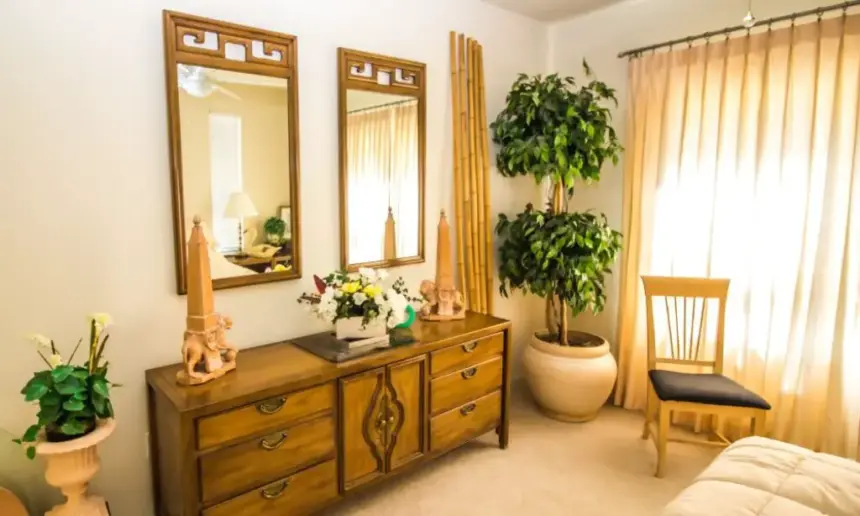 Wooden dresser with two vertical mirrors over it.
