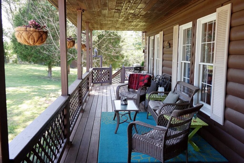 Front porch with blue carpet, table and chairs.