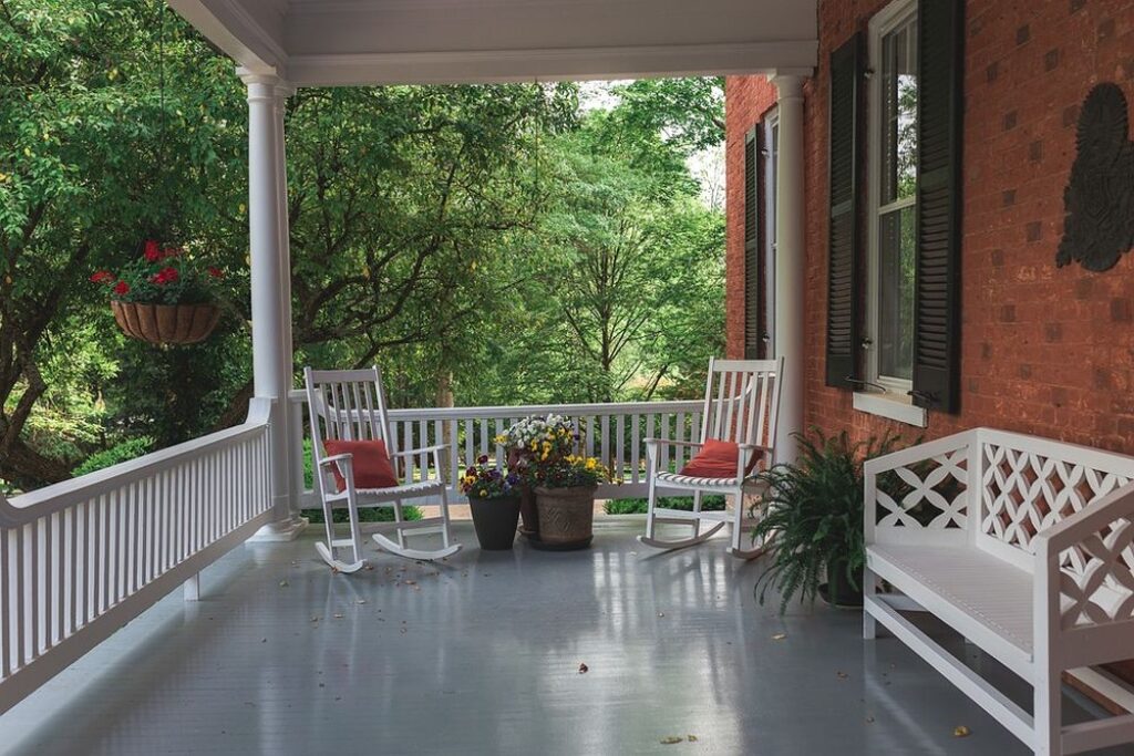 Front porch with white furniture and plants.