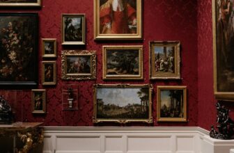 A red wall with a number of art paintings.